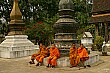 Young monks sit around a stupa in Luang Prabang; Laos